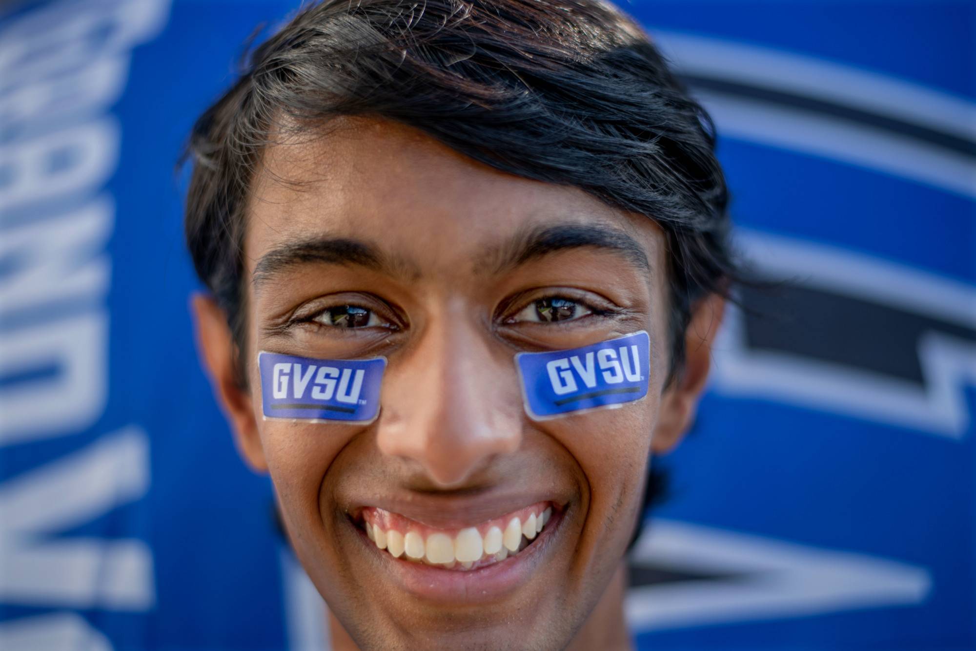 A student smiles with GVSU stickers on their face